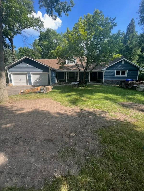 Blue vinyl sided home with white two-car garage, new windows, and manicured lawn