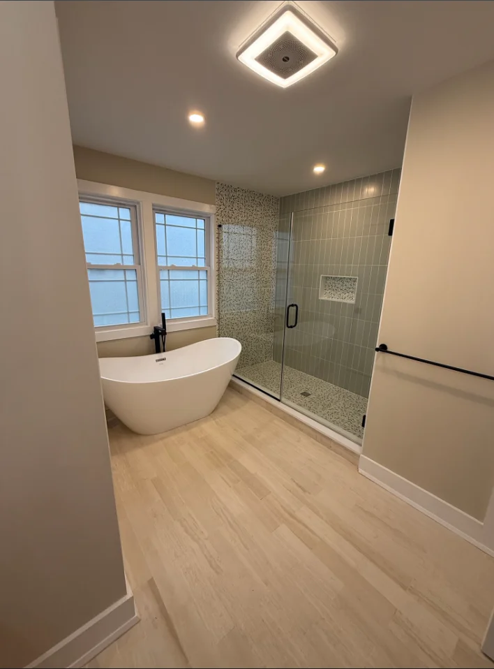 Modern bathroom with freestanding tub, frameless glass shower, and vinyl plank flooring