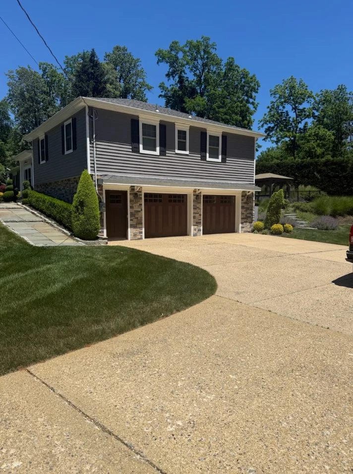 Two-story home with dark siding, stone veneer, and two-car garage with brown doors
