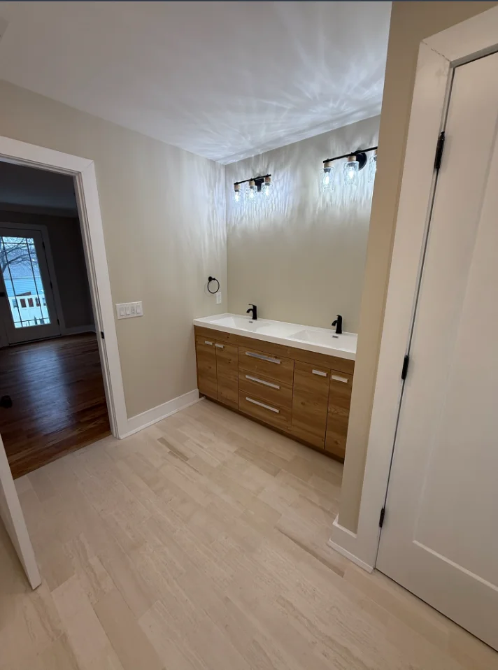 Dual-sink bathroom vanity with wood cabinetry, white quartz top, and recessed ceiling lights
