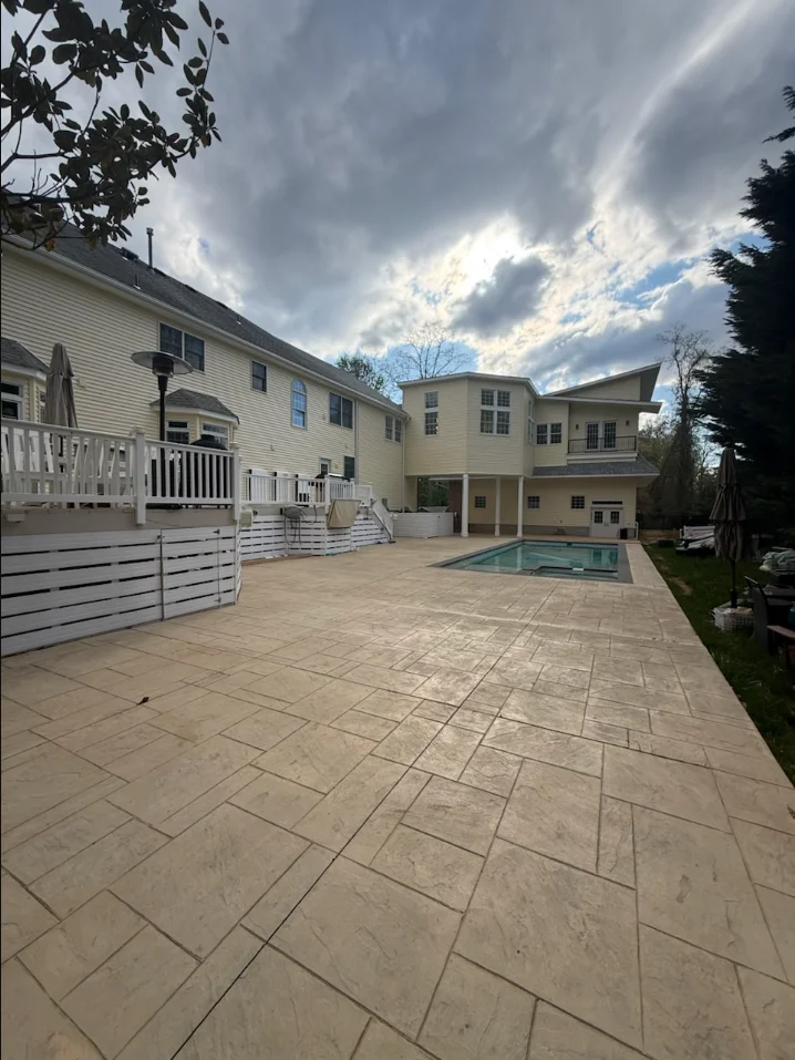 Herringbone paver patio with in-ground pool and white vinyl railings adjacent to multi-level home