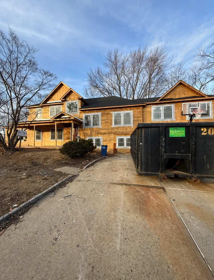 Two-story brick home with black roof, white-trimmed windows, and attached garage