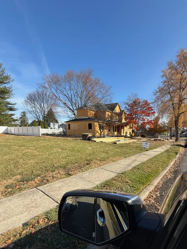 Brick Victorian home with concrete walkway, manicured lawn, and autumn trees