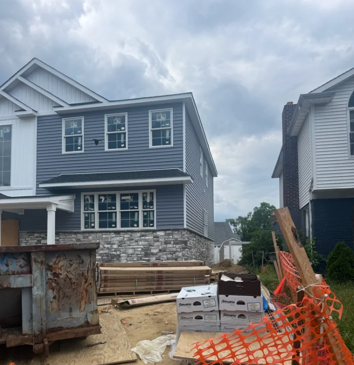 Two-story home with blue siding and stone veneer foundation during construction phase