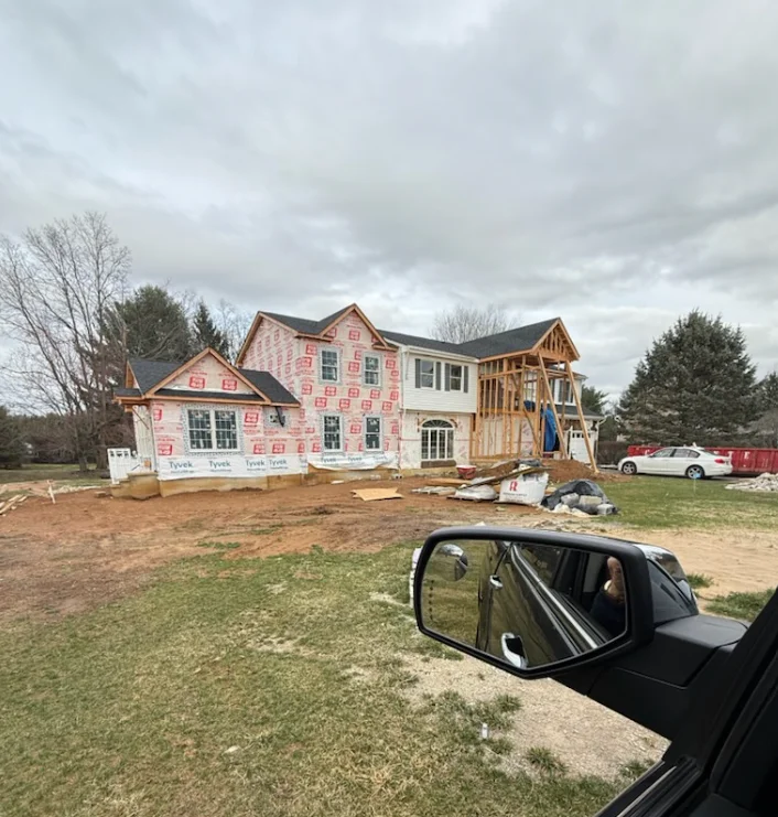 A newly completed custom home addition on a residential property in Holmdel, NJ, showing a seamless connection between the original structure and the new framed and sided exterior. The addition extends the rear of a two-story home with matching roofline and siding.
